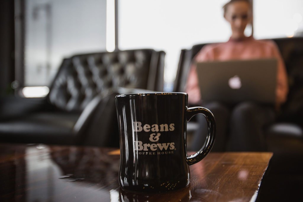 Person sitting down using a laptop computer with a coffee mug in the foreground